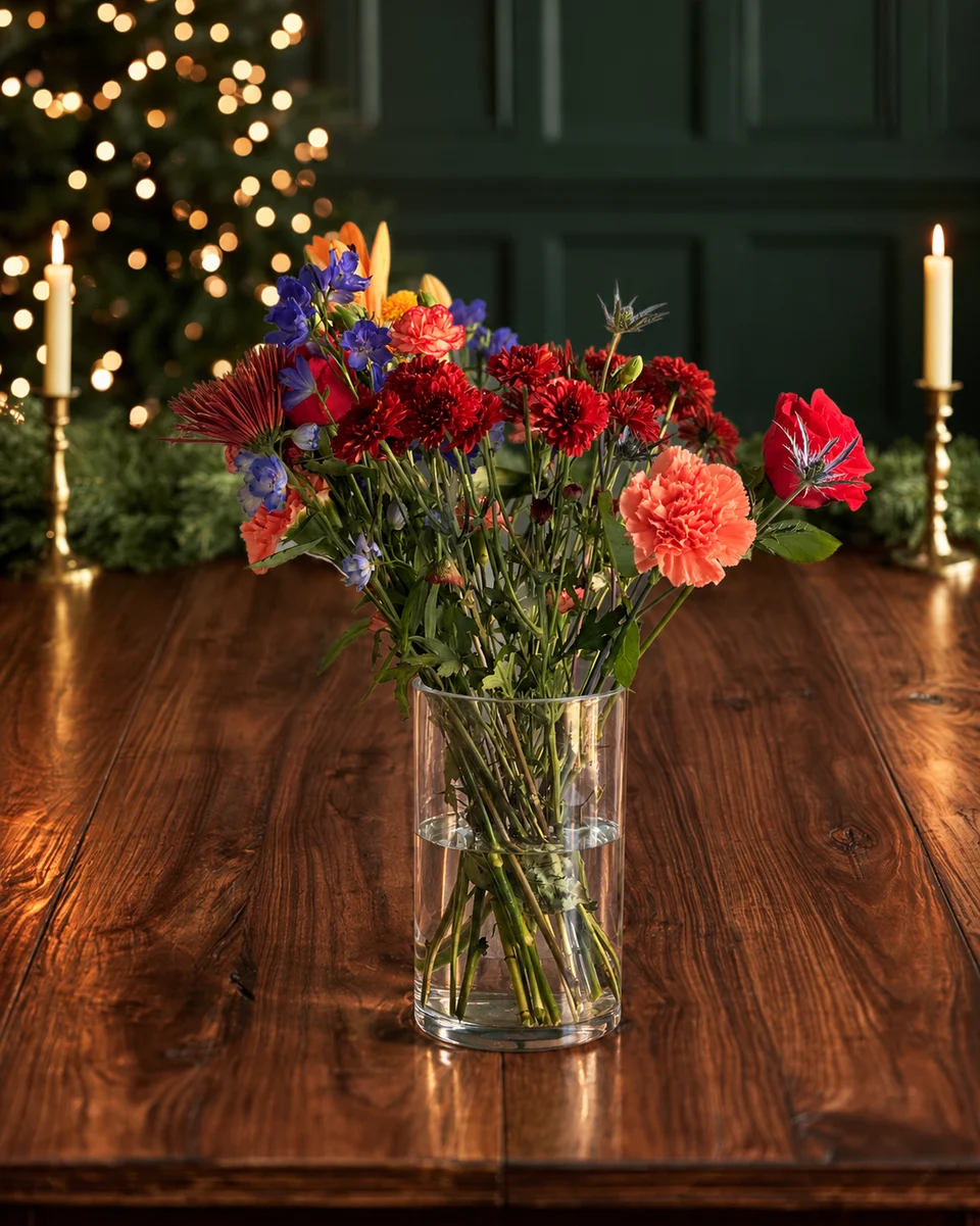 Illustrative test example: Mixed arrangement in a glass vase on a walnut Christmas table with candlesticks and a garland