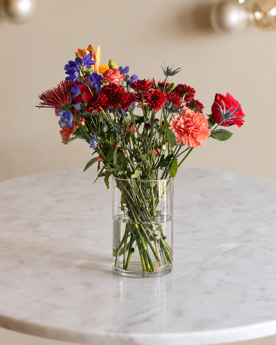 Illustrative test example: Mixed arrangement in a glass vase on a white marble table with silver baubles above