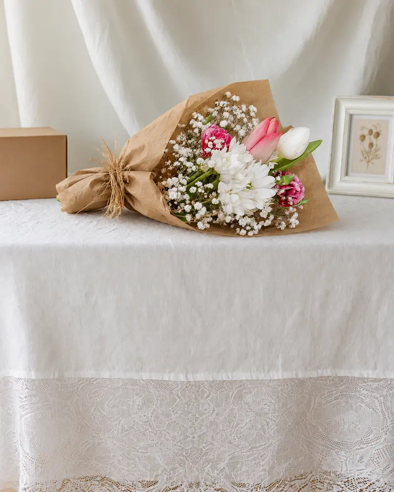 Example with sample flowers: a wrapped bouquet in the Gift table · white linen room, kept as made